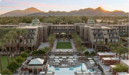 Ariel view of hotel at sunset with palm trees and a large pool